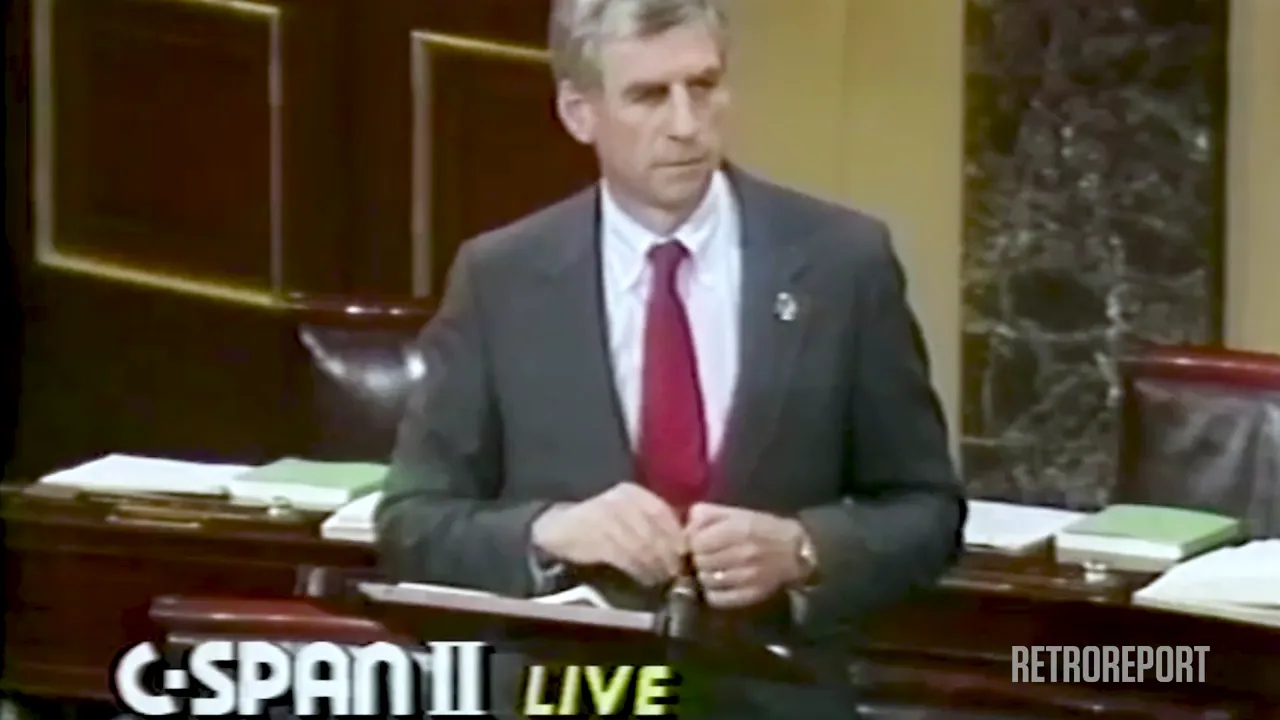 A man in a suit and tie stands at a podium in a chamber. Text on screen reads "C-SPAN II LIVE" and "RETROREPORT".
