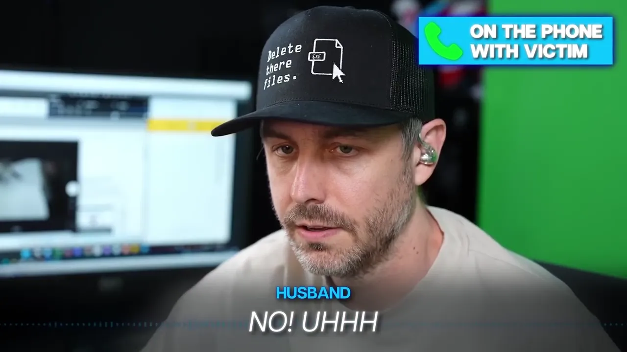 A man wearing a black hat with text and an icon on it, with "ON THE PHONE WITH VICTIM" text on screen.